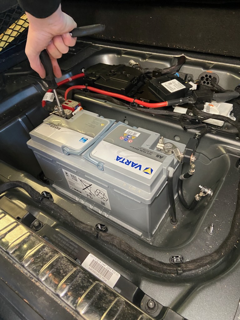 Tekniker kobler batteritester til bilbatteriet under drop-in batteribytte